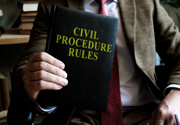 Man in a suit holding a book titled "Civil Procedure Rules"