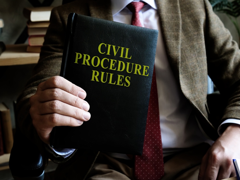 Man in a suit holding a book titled "Civil Procedure Rules"